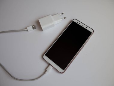 Şarj etmek için beyaz Usb kablosuna sahip bir akıllı telefon