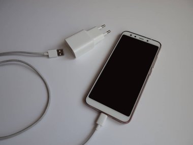 Şarj etmek için beyaz Usb kablosuna sahip bir akıllı telefon
