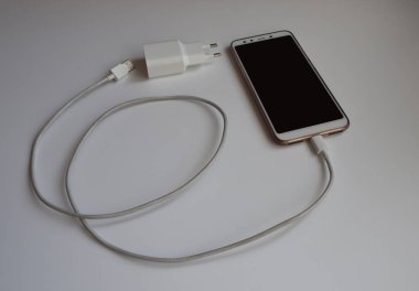 Şarj etmek için beyaz Usb kablosuna sahip bir akıllı telefon