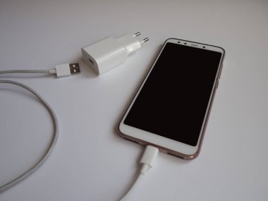 Şarj etmek için beyaz Usb kablosuna sahip bir akıllı telefon