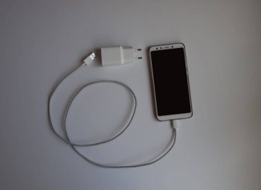 Şarj etmek için beyaz Usb kablosuna sahip bir akıllı telefon