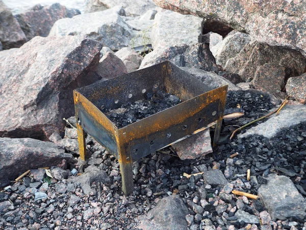 Empty metal brazier for camping on the rocks background