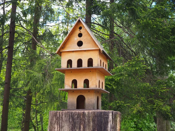 树桩上的多层木制雕刻鸟楼 是公园内鸟类的饲养者 — 图库照片