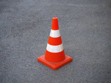 Kırmızı ve beyaz çizgili trafik konisi bir asfalt yolda. Yol yapım işlerini yürürken, trafiği niçin çizerken ya da acil durum ve trafik kazalarını belirlemede çit olarak kullanılır.