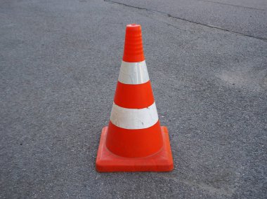 Kırmızı ve beyaz çizgili trafik konisi bir asfalt yolda. Yol yapım işlerini yürürken, trafiği niçin çizerken ya da acil durum ve trafik kazalarını belirlemede çit olarak kullanılır.