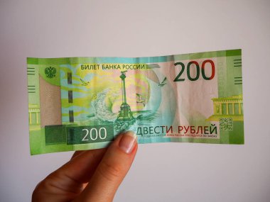 Bir kadının elinde iki yüz ruble değerinde yeni bir Rus banknotu var. Rus ulusal para birimi notu. Nakit kağıt para.