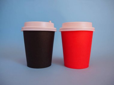 Kopya alanı ile iki kağıt paket kahve fincanları Mockup. Plastik kapaklı tek kullanımlık kağıt kabın yakından görünümü. Mavi arka planda kırmızı ve kahverengi fincansabah kahvesi. Boş polistiren kahve içme kupa mockup ön görünüm. Berrak plai