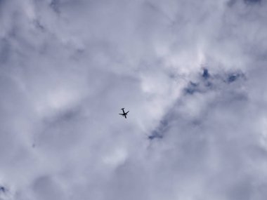 Bulutlu beyaz gökyüzünün arka planında uçak silueti. Yolcu uçağı bulutlu gökyüzü arka planda yüksek uçuyor.