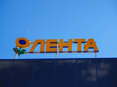 Saint-Petersburg, Rusya. 07.07.2019. Hipermarket Lenta mavi gökyüzüne karşı ayçiçeği logolu tabela. Lenta, Rusya'nın en büyük perakende zincirlerinden biri ve ülkenin en büyük ikinci hipermarket zinciridir. Hipermarketlere ek olarak, 