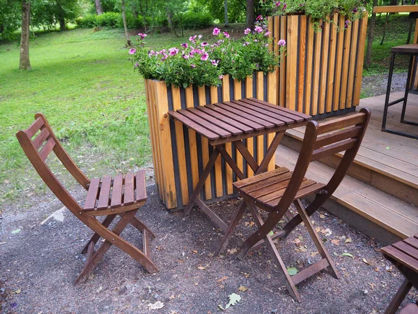 Yeşil bitki ve çiçek arka plan üzerinde parkta sokak yaz kafe terasında ahşap masa ve sandalyeler