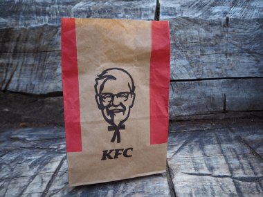 St. Petersburg, Rusya. 07.16.2019. Kentucky Fried Chicken kağıt torba gri ahşap bankta. Kfc, merkezi ABD'de bulunan bir fast food restoran zinciridir..