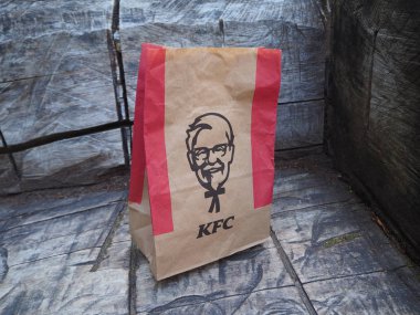 St. Petersburg, Rusya. 07.16.2019. Kentucky Fried Chicken kağıt torba gri ahşap bankta. Kfc, merkezi ABD'de bulunan bir fast food restoran zinciridir..