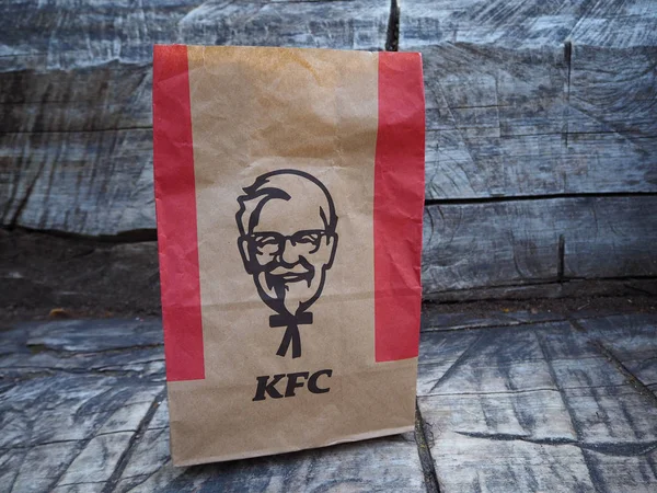 St. Petersburg, Rusya. 07.16.2019. Kentucky Fried Chicken kağıt torba gri ahşap bankta. Kfc, merkezi ABD'de bulunan bir fast food restoran zinciridir..