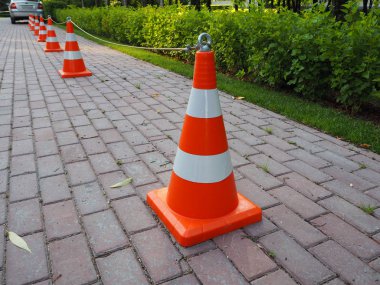 Turuncu ve beyaz çizgili trafik konileri birbirine zincirlenmiş. Yol yapım işlerini yürürken, trafiği niçin çizerken ya da acil durum ve trafik kazalarını belirlemede çit olarak kullanılır..