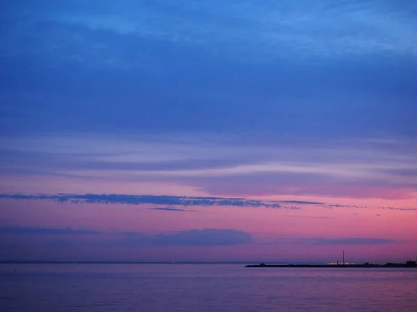 Twilight sky at the colorful blue and pink sunset and reflection in the water of the sea. Panoramic landscape on the dusk.