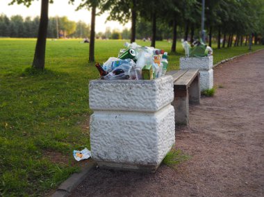 Her türlü çöplükte dolu bir parkta atık kutuları taşıyordu. İnsanlar çöp geride bırakır. Çevre kirliliği. Plastik atık ekolojik sorunu.