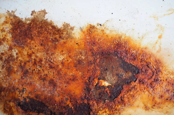 Brown, black and yellow rust and dirt on white enamel. Rusted brown and white abstract texture. Corroded white metal background. Rusted white painted metal wall. Rusty metal surface with streaks of rust. Rusty corrosion. Old metal iron rust backgroun