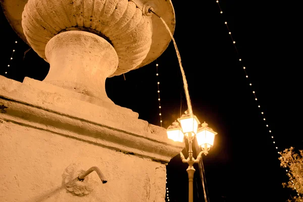 Una fontana di notte con l'acqua che scende e la luce — Foto Stock