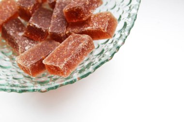 Beyaz bir arka plan üzerinde cam bir tabak ta ev yapımı kırmızı-turuncu marmelat şeker. Ahududu meyve jöle şekerler. Tatil kutlama tebrik kartı için. Yemek kitabı için. 