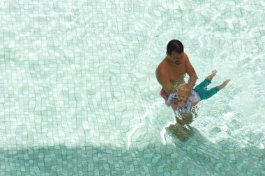 Baba mutlu kızına yüzmeyi öğretiyor.