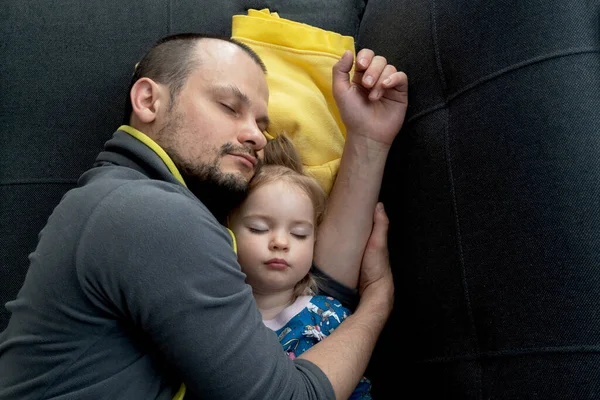 Young handsome caucasian father sleeps hugging his cute little child