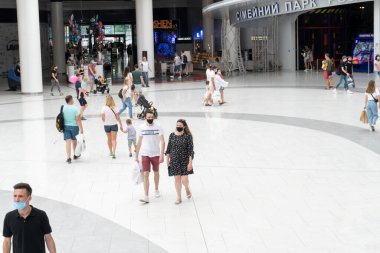 Koruyucu maskeli beyaz insanlar Lavina alışveriş merkezinde yürüyor.,