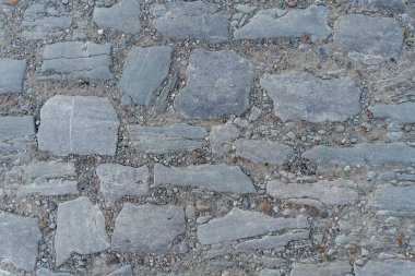 Taş yola yakın, farklı büyüklükte taşlar ve çimenler var aralarında.,