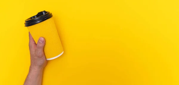 Καφές takeaway σε κίτρινο χάρτινο κύπελλο με μαύρο καπάκι στο αριστερό καυκάσιο είναι κίτρινο φόντο Φωτογραφία Αρχείου