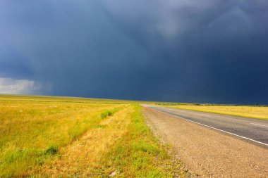 alan ve ufukta bir kara bulut ile asfalt yol