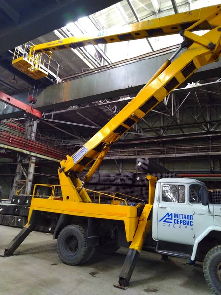 yellow tower vehicle raised the cradle on the bridge crane in the workshop