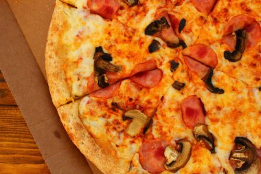 Masadaki kutuda mantarlı ve sosisli taze pizza.