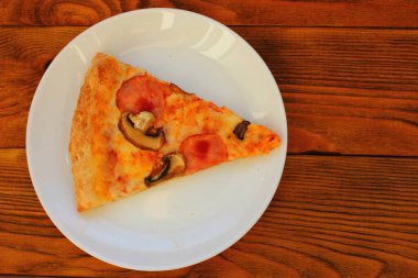 Masadaki beyaz tabakta bir dilim pizza.