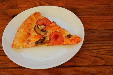 Masadaki beyaz tabakta bir dilim pizza.