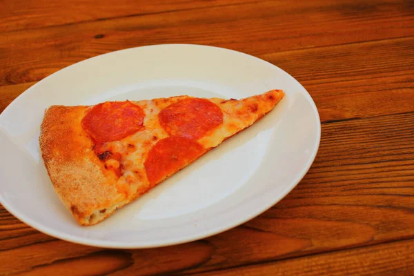 桌上白盘上的一片披萨 — 图库照片