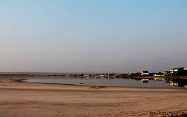 Kırım. Tuz gölünün kumlu kıyısı. Mesafede evler var. Sıcak ve terk edilmiş..