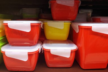 Sıkı kapaklı kırmızı gıda kapları. Yiyecek ve pişmiş gıda saklamak için özel kutular. Mağaza raflarında farklı boyutlarda plastik kaplar.