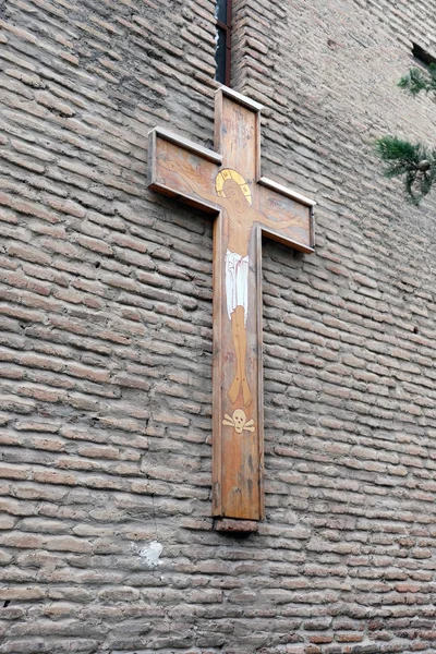 Natural wooden cross on a brick wall. Cross on the wall of an ancient temple, side view. The concept of religion and a symbol of Christianity.
