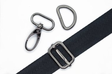 Çanta ve sırt çantaları yapmak için dikiş metal parçaları. Karabina, beyaz arka plan üzerinde koyu nikel renkte yarım halka ve uzunluk ayarlayıcısı. Çanta farklı yapmak için siyah bant.