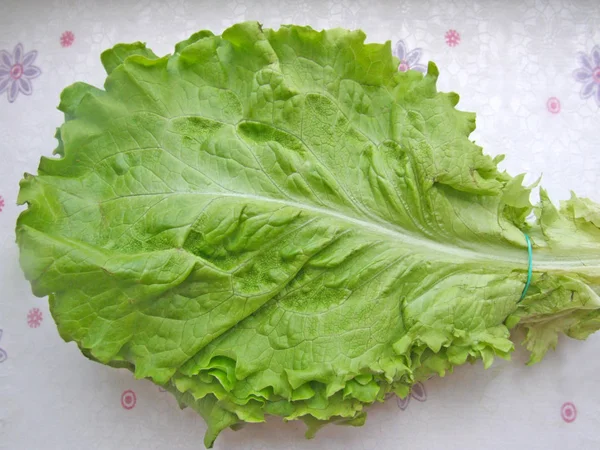 Green fresh lettuce leaves closeup. A bunch of lettuce leaves on the table, top view. Healthy and wholesome food for vegetarians.