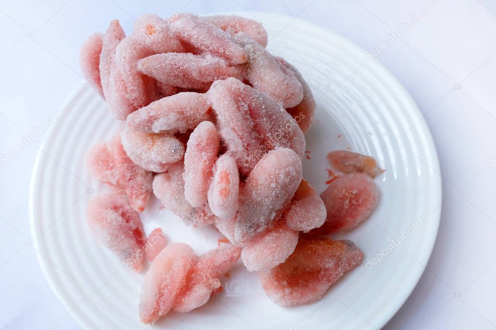 Frozen boiled shrimps lie on a white plate. Shrimps in ice glaze are defrosted on a plate.