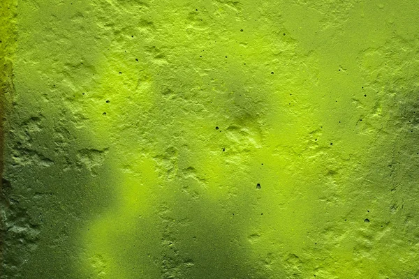 The texture of the unevenly painted wall is light green. The wall with irregularities and dimples. The background of the green concrete wall.