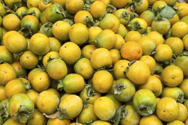 Sarı olgunlaşmamış hurma arka planı. Atina'da pazar tezgahında Trabzon.