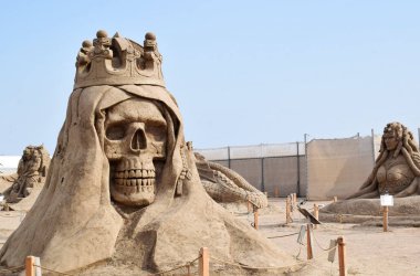 Lara Beach, Sandland Sand Sculpture Festival. View of big sand sculpture of mythological characters. The skull is a symbol of death and danger, as well. clipart
