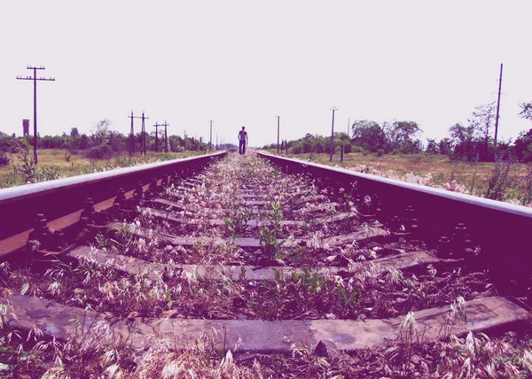 Railway road. Man walk away on railroad. Selective focus, toning. Traveler man on railroad.
