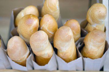 Rafta fırınlanmış somunlar. Her somun ekmek gri bir kese kağıdına sarılır. Fransız somunu altın kabuklu üst manzaraya fırında.