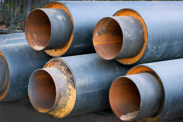 Steel pipes with thermal insulation in the shell of a plastic pipe at a construction site, closeup. Heat-insulated steel pipes for laying heating sewerage. Installation of a heating system in the city