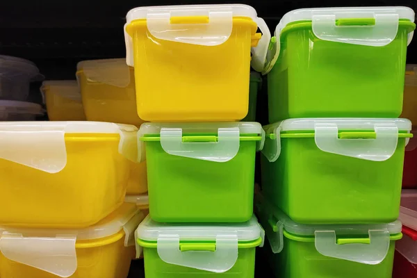 Yeşil ve sarı plastik kapaklı kaplar, yakın çekim. Evrensel yiyecek konteynerleri. Yiyecek ve sebze depolamak için kapaklı parlak plastik kutular. Mağazadaki modern mutfak aletleri..
