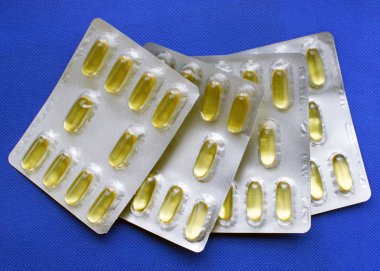 Mavi arka planda su toplayan Omega 3 kapsülleri. Düzgün beslenme, besin takviyeleri, sağlıklı beslenme kavramı..