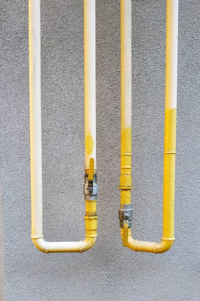 Żółte Pionowe Rury Metalowe Żurawiami Pod Szarą Ścianą — Zdjęcie stockowe