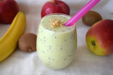 Kivi ve muzlu, iştah açıcı süt kokteyli. Kivi, muz ve elmayla birlikte sağlıklı bir içecek. Meyveli masada bir bardak meyve suyu..